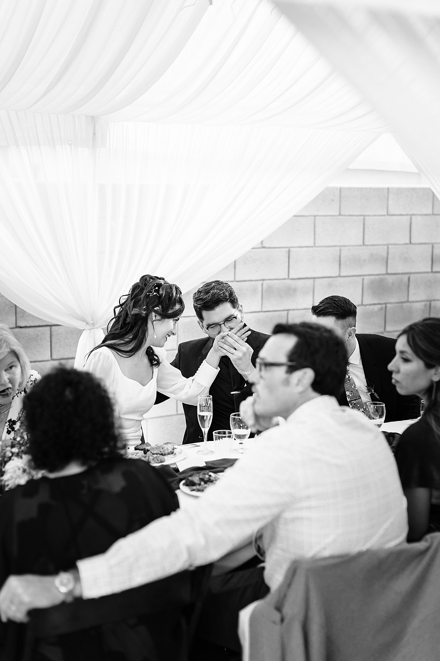 Groom kissing bride's hand at reception