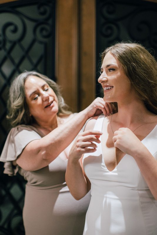 Mother of bride putting necklace on bride